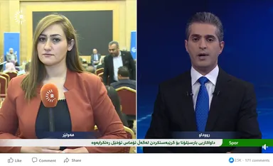 Split-screen Facebook video screenshot with a female reporter on one side and a male news anchor on the other, with a Kurdish news ticker at the bottom.
