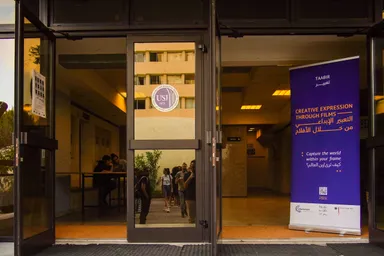 Building entrance with a "TAABIR تعبير – Creative Expression Through Films" banner beside a glass door marked "USJ 1875".