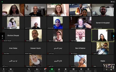 Video conferencing grid showing numerous participants in individual tiles, with on-screen meeting controls at the bottom.