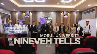 A group of people posing for a photo in a conference room, with overlaid text reading "MOSUL UNIVERSITY", "NINEVEH TELLS", "2024" and a "MOSUL TELLS" logo.