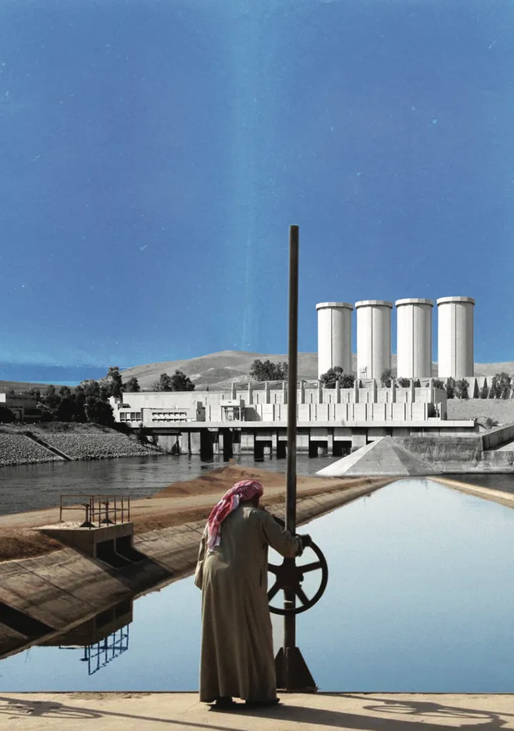 A person in traditional dress operates a large valve wheel beside a canal, with a dam and four cylindrical towers in the background.