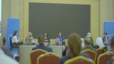 Six panelists sit on a stage behind a blank screen, viewed over the heads of an audience, with "elbarlament" banners on either side.