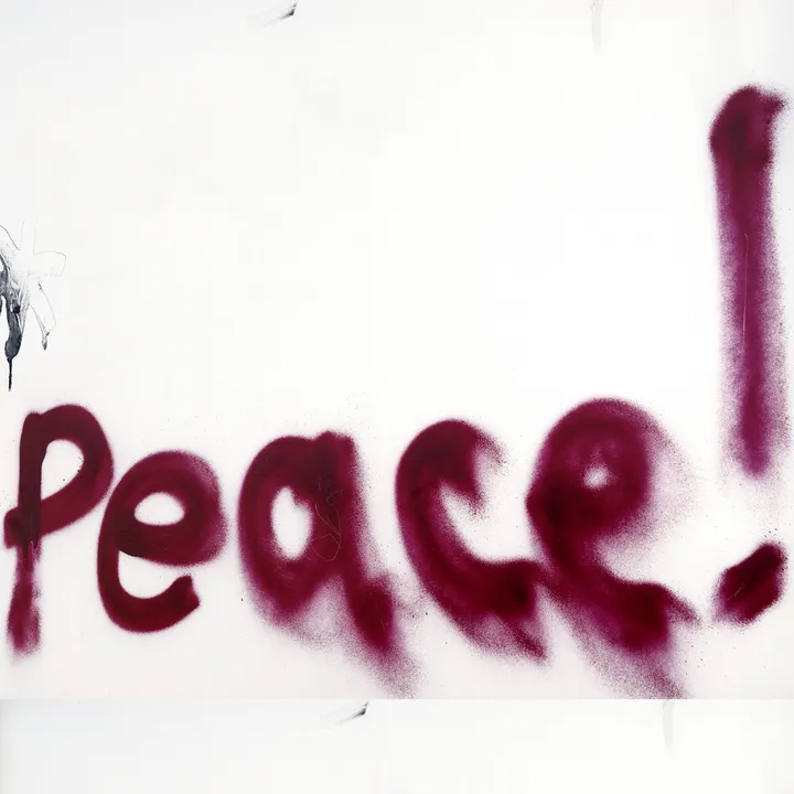 Spray-painted text reading "Peace!" in dark pink on a white wall.