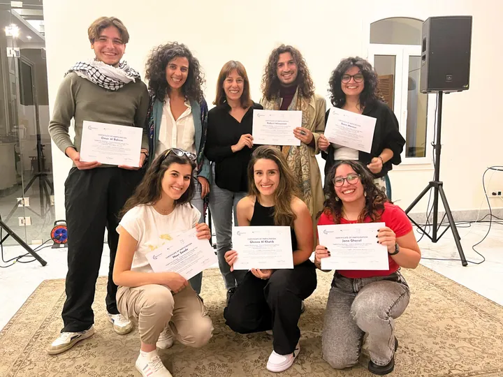A group of people pose indoors holding papers reading "Certificate of Participation".