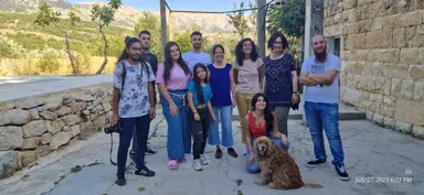 Group photo of people posing outdoors in front of hills with a dog sitting in the foreground, timestamped "Zk July 27, 2023 6:03 PM".